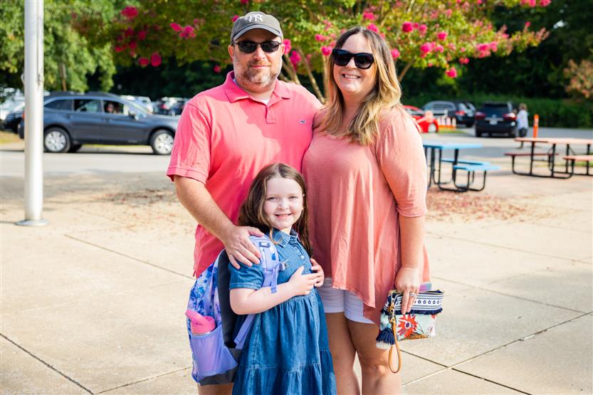 Three people stand together and smile